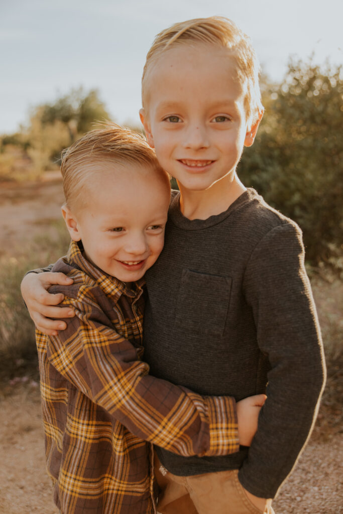 Two young brothers hug each other and smile genuinely. Little kid posing inspiration and ideas. #Arizonfamilyphotographer #Phoenixphotolocations #superstitionmountains #familyphotographer #ChelseyMichellePhotography #Scottsdalephotographer #familyphotosinspo #LostDutchmanStatePark