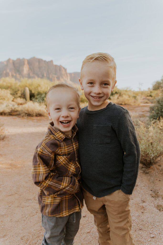 Brothers wearing cozy fall long sleeves put their arms around one another and smile for fall family photos. #Arizonfamilyphotographer #Phoenixphotolocations #superstitionmountains #familyphotographer #ChelseyMichellePhotography #Scottsdalephotographer #familyphotosinspo #LostDutchmanStatePark