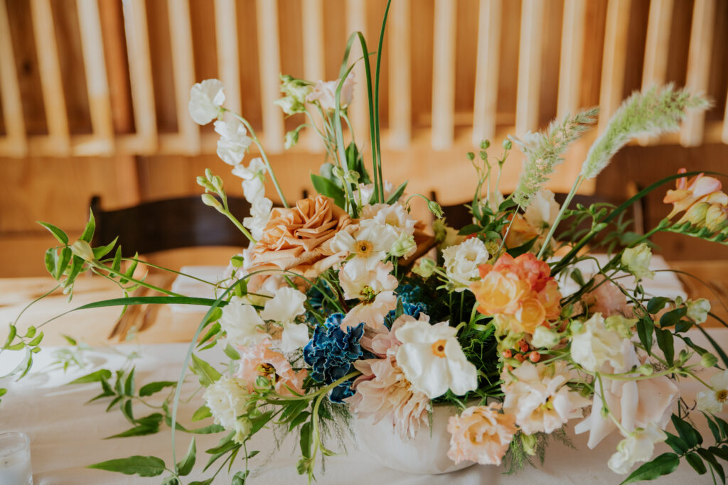 Stunning pink, orange, and blue floral arrangement on the center of a table in The Paseo’s indoor dining area. #ChelseyMichelleCoPhotography #Arizonaweddingphotographer #Phoenixweddingphotographer #Apachejunctionwedding #ThePaseo #weddingatThePaseo #Gilbertphotographer #Arizonadestinationwedding