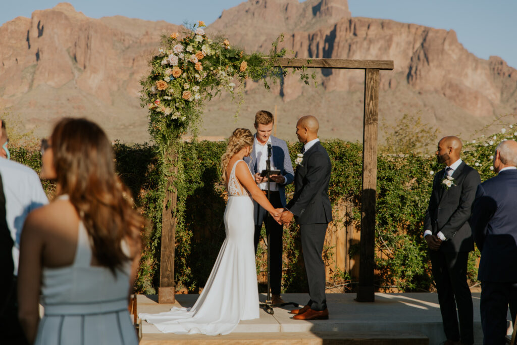 Beautiful photo of the bride and groom holding hands before saying their wedding vows in Apache Junction, Arizona. #ChelseyMichelleCoPhotography #Arizonaweddingphotographer #Phoenixweddingphotographer #Apachejunctionwedding #ThePaseo #weddingatThePaseo #Gilbertphotographer #Arizonadestinationwedding