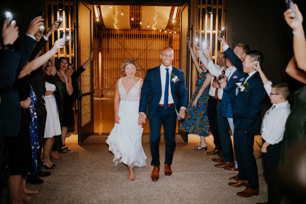 The bride and groom laugh as they make an exit from The Paseo wedding venue at the end of their summer wedding day. #ChelseyMichelleCoPhotography #Arizonaweddingphotographer #Phoenixweddingphotographer #Apachejunctionwedding #ThePaseo #weddingatThePaseo #Gilbertphotographer #Arizonadestinationwedding