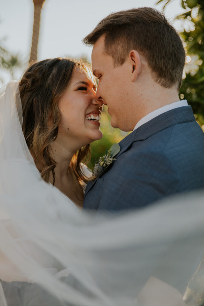 Close up shot of smiling bride and groom during bridal photo shoot with veil blowing in the wind. Romantic LDS wedding photo inspiration #ChelseyMichelleCoPhotography #Arizonaweddingphotographer #Phoenixphotographer #Mesaphotographer #Gilbertphotographer #ArizonaLDSwedding