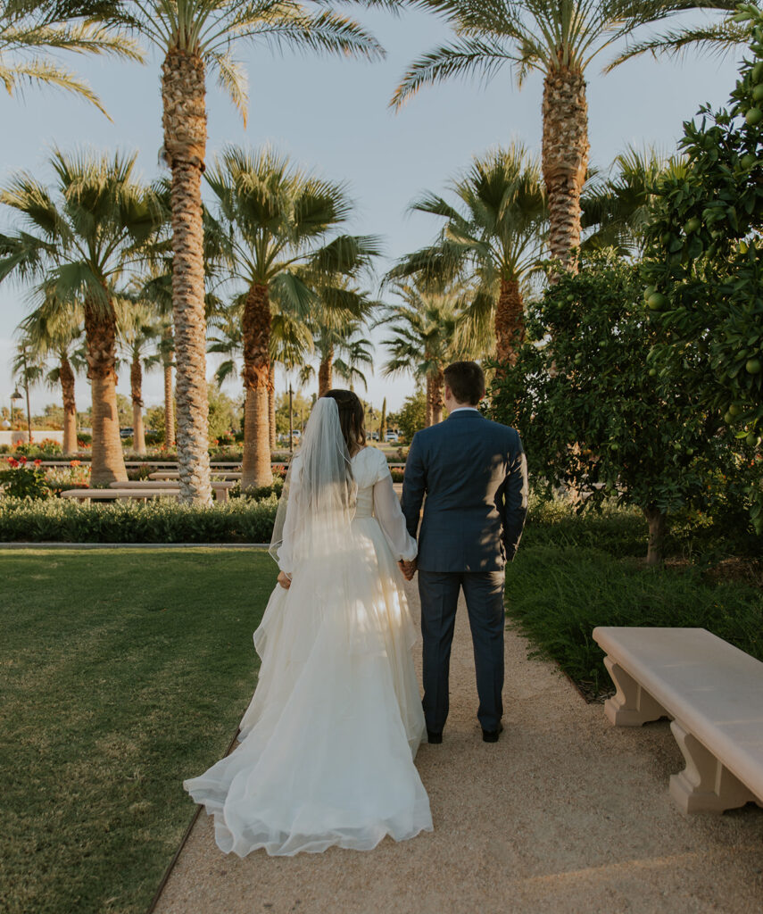 Bride and groom standing with their backs to the camera holding hands. Bridal photos at Mesa LDS Temple. #ChelseyMichelleCoPhotography #Arizonaweddingphotographer #Phoenixphotographer #Mesaprohotgrapher #Gilbertphotographer #ArizonaLDSwedding