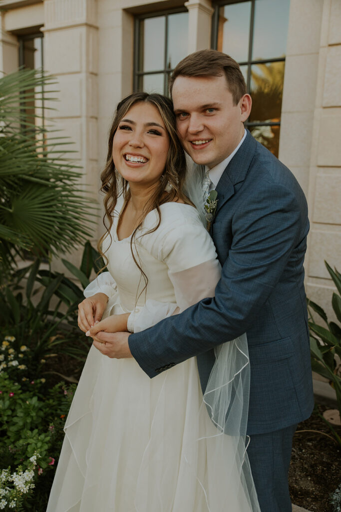 Wedding photo of bride and groom standing in front of the Mesa Arizona temple. Casual wedding photo pose candid bridal photos #ChelseyMichelleCoPhotography #Arizonaweddingphotographer #Phoenixphotographer #Mesaphotographer #Gilbertphotographer #ArizonaLDSwedding #MesaArizonaTemple