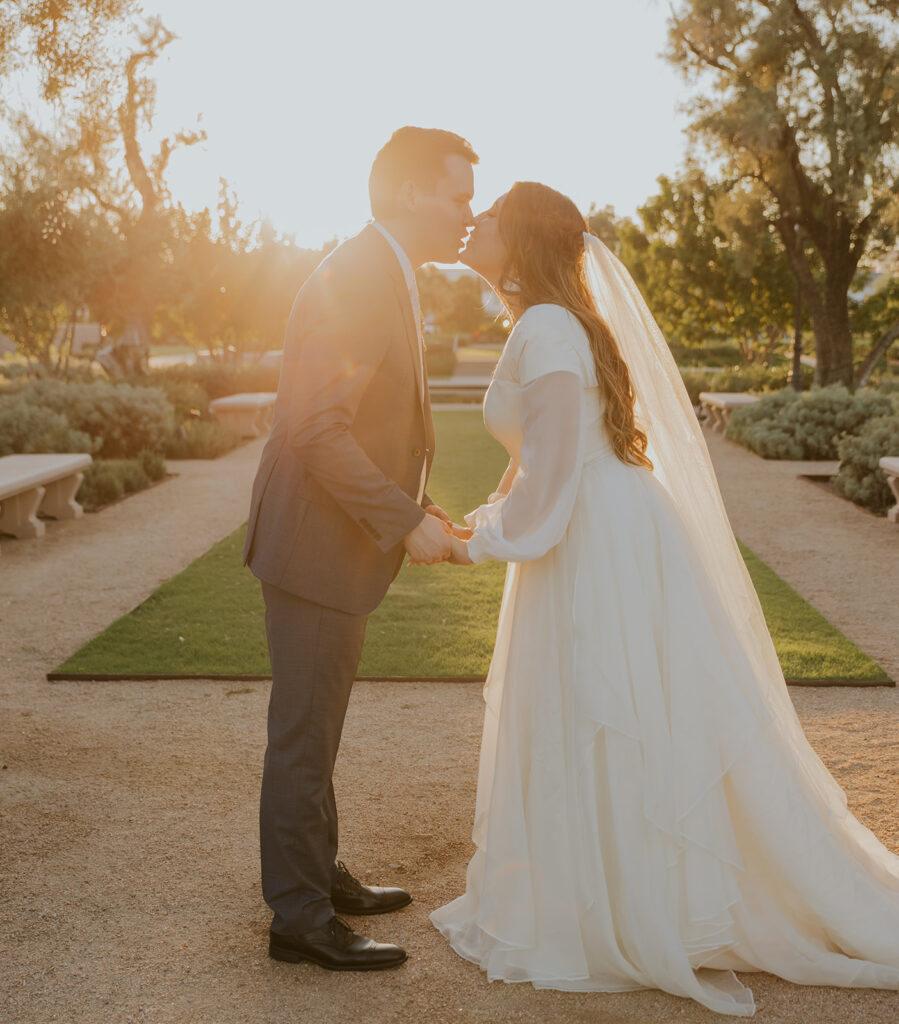 Golden hour wedding photo of bride and groom kissing on steps of Mesa Arizona temple during first look photo shoot. #ChelseyMichelleCoPhotography #Arizonaweddingphotographer #Phoenixphotographer #Mesaphotographer #Gilbertphotographer #ArizonaLDSwedding #MesaArizonaTemple