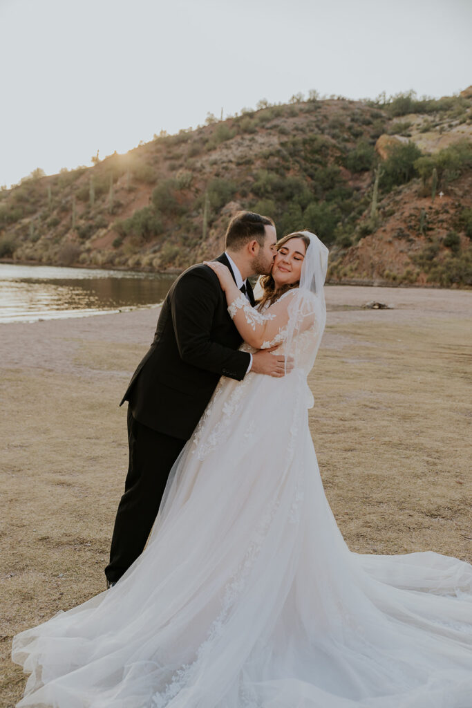 A handsome groom gently dips his bride while kissing her on the cheek during a bridal photo session with Chelsey Michelle Co Photography. 
#ChelseyMichelleCoPhotography #ArizonaWeddingPhotographer #PhoenixPhotographer #MesaPhotographer #BridalPhotos #SaguroLake
