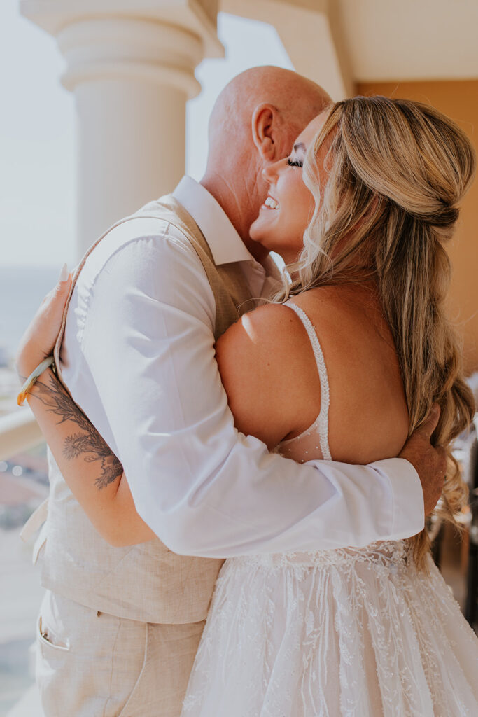 The most darling bride is hugged by her father in an image taken by Chelsey Michelle Co Photography. She grins from ear to ear during this exchange. Tender family wedding moments. #DestinationWedding #ChelseyMichelleCoPhotography #SummerWedding #FloridaWedding
