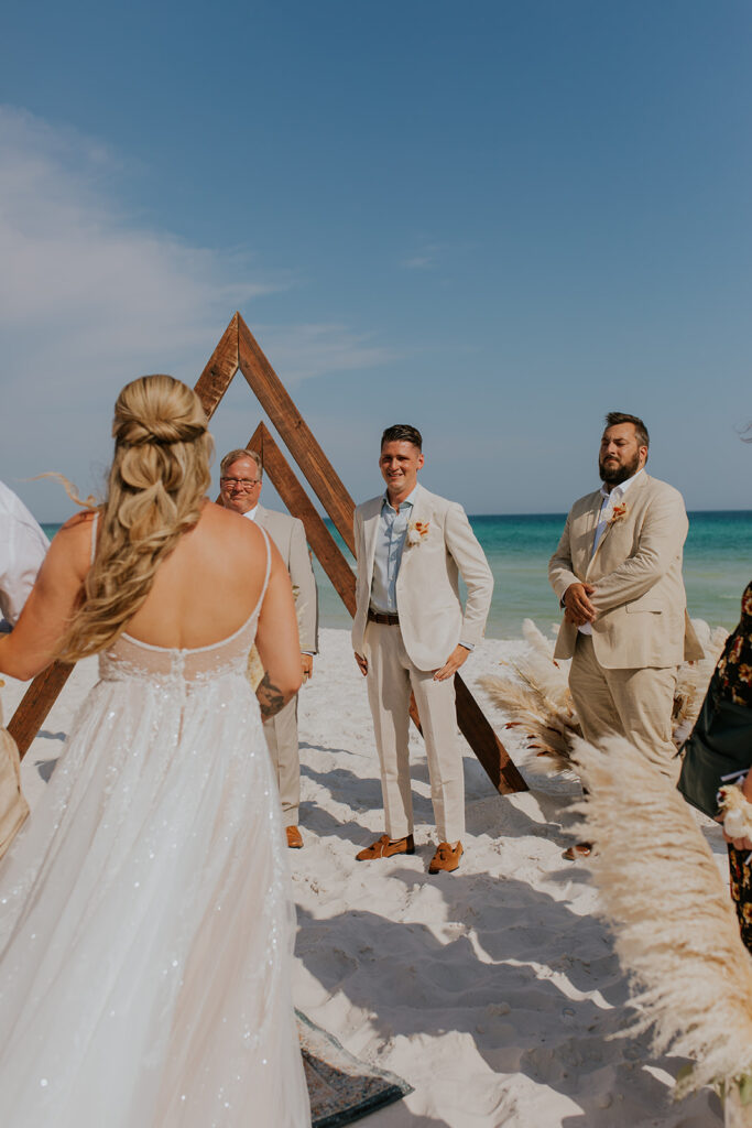 An image of a groom as he watches his bride walk down the aisle on her dad’s arm. The groom looks so happy to see his stunning bride walking towards him. Chelsey Michelle Co Photography captures the small, meaningful moments throughout the day. #DestinationWedding #ChelseyMichelleCoPhotography #SummerWedding #FloridaWedding
