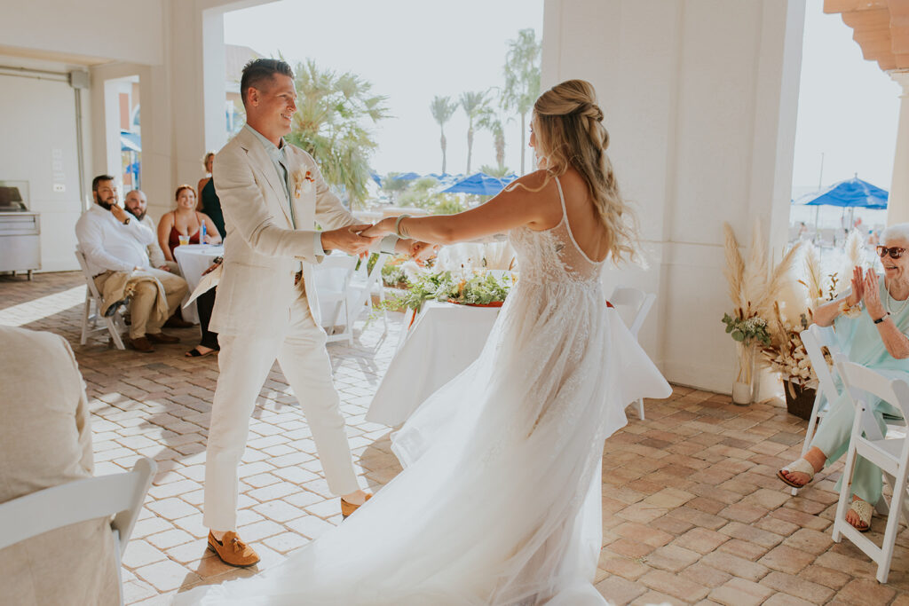 The happiest bride and groom dance together on an outdoor patio during their reception. Onlookers smile at the newlywed couple as they share this dance. Bridal hair inspiration.#DestinationWedding #ChelseyMichelleCoPhotography #SummerWedding #FloridaWedding
