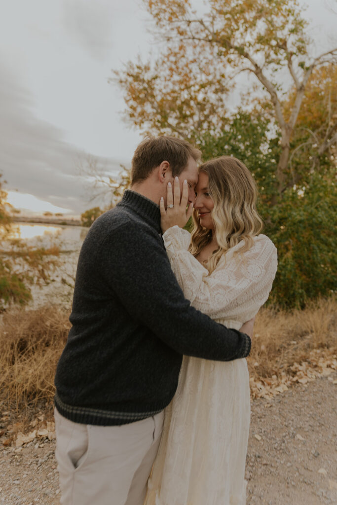 The couple lovingly embrace for engagement photos in East Gilbert, with a beautiful overcast backdrop and green trees. Arizona wedding portraits love bride groom #engagementphotosgilbert #azbrides #couplephotography #arizonaweddings #chelseymichellephotography
